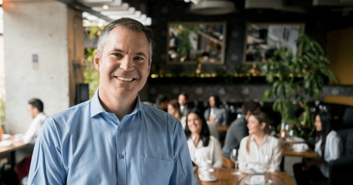 Smiling businessman in a restaurant, representing flexible business loan solutions for New York merchants.