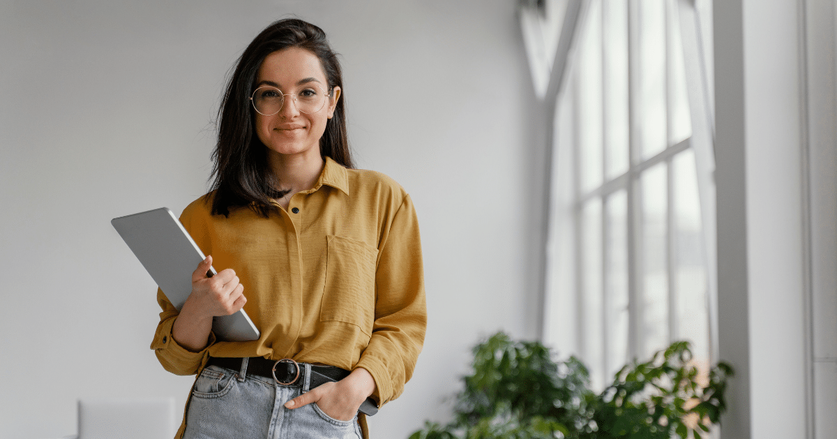 Young businesswoman holding a tablet in a bright office, emphasizing the importance of location in real estate for small businesses.